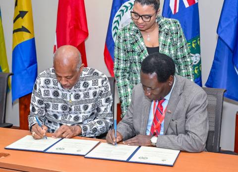 Professor Sir Hilary Beckles, Vice-Chancellor of The UWI, and Professor Andrew Haruna, Secretary General of CVCNU, sign the agreement as Mrs Delrene Liverpool-Young, University General Counsel for The UWI, looks on.