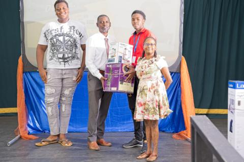 Student intern Mr. Ethan Padmore (second right) presents The Barbados Seventh-day Adventist Secondary School, Principal Mr. Winslow Benn and students with the prize for the secondary school with the third-highest participation, sponsored by Kooyman Barbados.